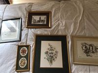 Image showing all five framed artworks laid on fabric surface: includes botanical bouquet, architectural sketches, floral ovals, and horse sketch.