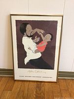 Front view of framed art print showing a man holding a child with purple background and signature 'Helen Oxenbury' below.