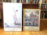 Framed prints side by side on a wooden floor with bookshelves background