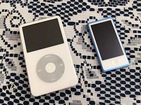 Front view of iPod Classic and blue iPod Nano on dark patterned cloth.
