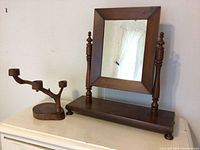 Front view of wooden rectangular tilt mirror with turned supports and base; wooden three-arm candle holder with organic branch shape.