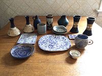 Full view of the 12 assorted stone and ceramic decorative items arranged on wooden table, showing varied shapes including vases, dishes, mug, and tile pieces.