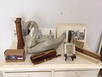Wooden swan sculpture, recorders, framed cityscape art prints, wooden flute and Eton radio on table
