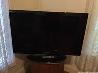 Front view of the Samsung 55-inch LED TV on a wooden stand with remote control on top.