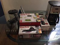 Overview of the small appliances and boxed items on a glass table