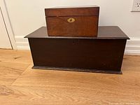 Two vintage wooden storage boxes stacked, larger dark box on bottom, smaller lighter box on top