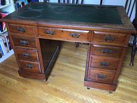 Front view of vintage desk with multiple drawers and brass hardware on wooden floor