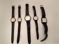 Full view of 5 wrist watches aligned side by side on a white background showing different dial shapes and black straps.