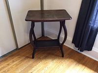 Full view of the wood table showing curved legs and lower shelf in corner placement.