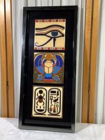 Full front view of the black shadow box frame containing the three Egyptian themed ceramic tiles arranged vertically.