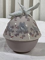 Front view of the domed covered dish with two white doves on top and painted floral design on the lid and base visible.