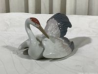 Front and side angle of Lladro porcelain swan figurine showing detailed wing and body coloring.