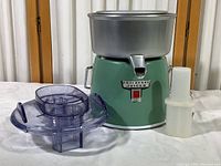 Full view of vintage Fujidenki juicer showing green metal base, aluminum bowl, clear plastic lid, and white plunger.