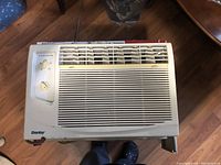 Front view of compact white window air conditioner with control panel and vent grille.