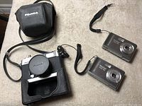 All three cameras together showing the Fujica 35mm in case and two Vivitar digital cameras.