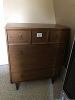 Front view of vintage wooden dresser showing four drawers with brass ring pull handles.