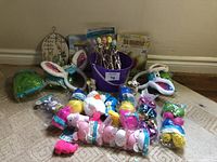 Wide view showing all Easter items arranged on a carpet including bunny ears, eggs, plush toys, bucket and grass.
