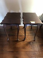 Two matching wooden end tables shown from a frontal angle on wooden flooring.