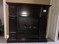 Full view of electric fireplace with dark wood mantel, showing the design and overall condition.