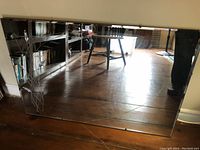 Clear view of entire rectangular mirror showing reflective surface, floor and furniture reflected within, highlighting overall condition and size.