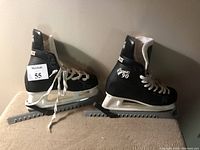 Side view of CCM Champion 90 black ice skates with white laces and blade guards on the blades.