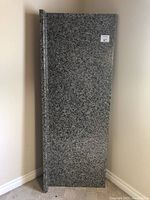 Full view of the granite bathroom vanity countertop leaning against the wall showing rectangular shape and thickness.