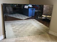 Full front view of the large vintage wall mirror resting against a wall revealing reflective surface and general size