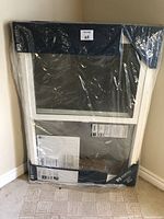 Front view of packaged white vinyl window showing overall shape and packaging