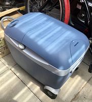 Blue and gray Mobicool wheeled cooler with ventilation fans on the lid, handle and wheels visible