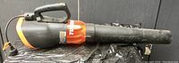 Orange and black Turbine brand electric leaf blower laid horizontally showing tubular design and handle.