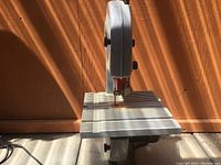 Front view of the electric band saw showing the ribbed support table and upright saw blade housing with adjustment knobs