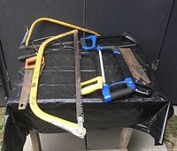 Seven hand saws displayed on black table, various sizes and frame and handle types visible.