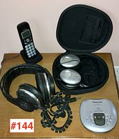 View of two stereo headphone sets, Panasonic portable CD player, and VTech cordless phone on wooden surface.