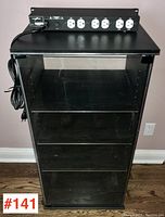 Front view of black stereo components cabinet with glass sides and shelves, Lightspeed power bar on top