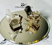 Pair of Swarovski crystal figurines on reflective surface showing rocking chair and gramophone detail