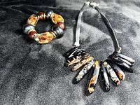 Photo showing the necklace with polished black and amber agate stones on black suede and the expandable amber color bead bracelet.