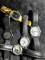 Top view of five vintage men's wristwatches arranged side by side, showing watch faces and bands.