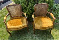 Front view of both chairs showing carved wooden frames, cane backs, and velvet seat cushions