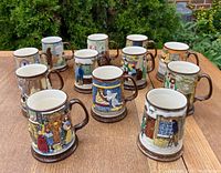 Set of twelve embossed and hand-coloured Beswick/Royal Doulton Christmas mugs arranged on a wooden table outdoors, showing detailed holiday scenes.