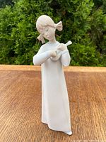 Front view of Lladro figurine showing girl holding violin and wearing long dress