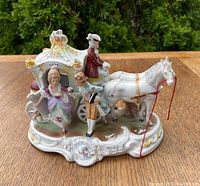 Porcelain figure group showing the front and side view of the horse-drawn carriage with figures, capturing the detailed painting and carriage design.