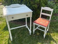 Photo showing small white desk and matching chair outdoors on grass.