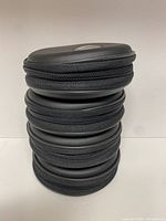 Stacked view of three round black zippered disc cases for GameCube.
