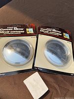 Two stick-on convex mirrors in original cardboard packaging, each 9.5 cm in diameter.