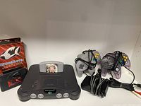 Setup shot of Nintendo 64 console, GoldenEye 007 cartridge, GameShark in box, two controllers, power adapter and AV cable