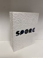 Front view of white embossed Spore collector's edition case with cut-out letters