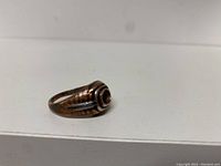 Front angled view of the copper ring showing the rounded rectangular bezel and small dark stone or detail in the center.