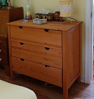 Front view of solid pine wood 3-drawer chest showing natural wood grain and integrated drawer handles.