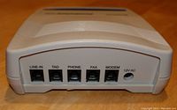 Close-up of back of the device showing 5 ports (LINE-IN, TAD, PHONE, FAX, MODEM) and 12V AC power input jack.