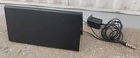 Black rectangular digital TV antenna with power adapter and cable, front view.